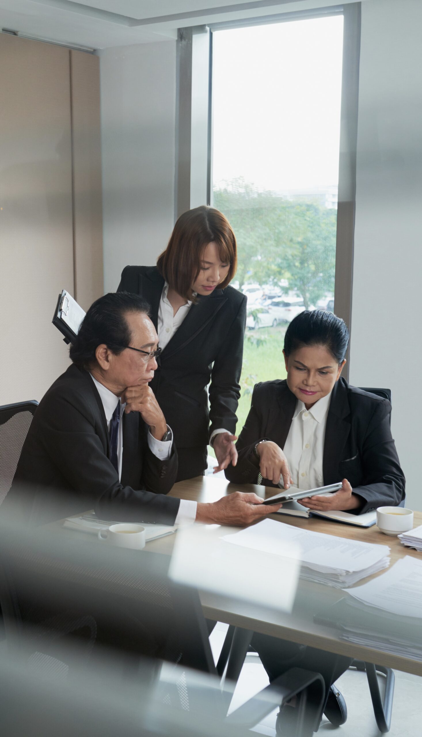 Vietnamese business team discussing document on tablet computer